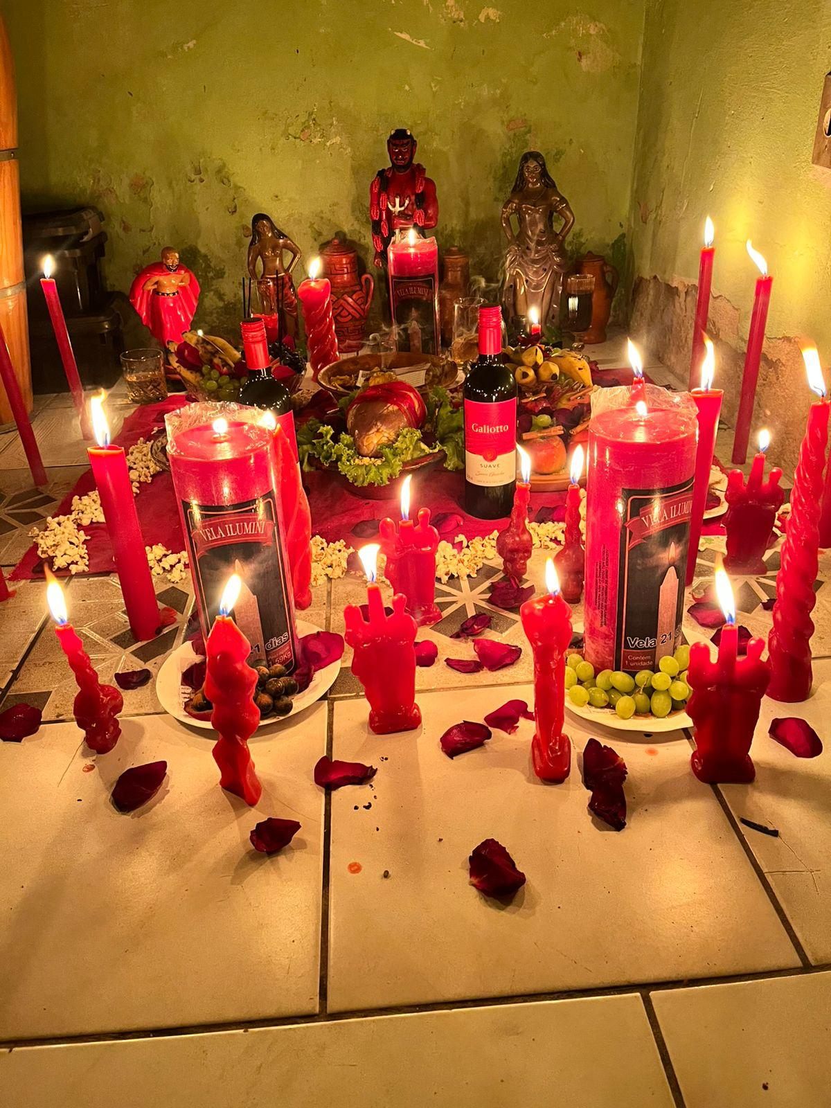 Altar preparado com velas vermelhas, pétalas de rosa e imagens